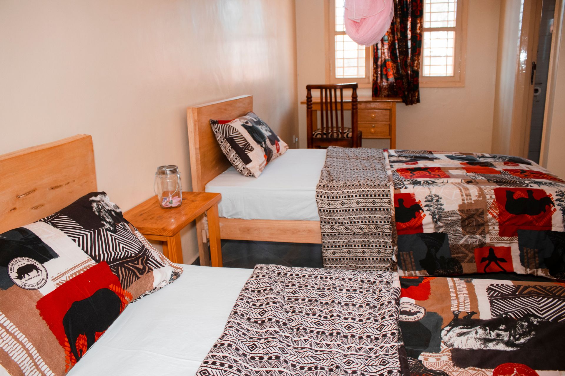 Colorful twin bedroom with unique African quilts and wooden furniture in Kampala, Uganda.
