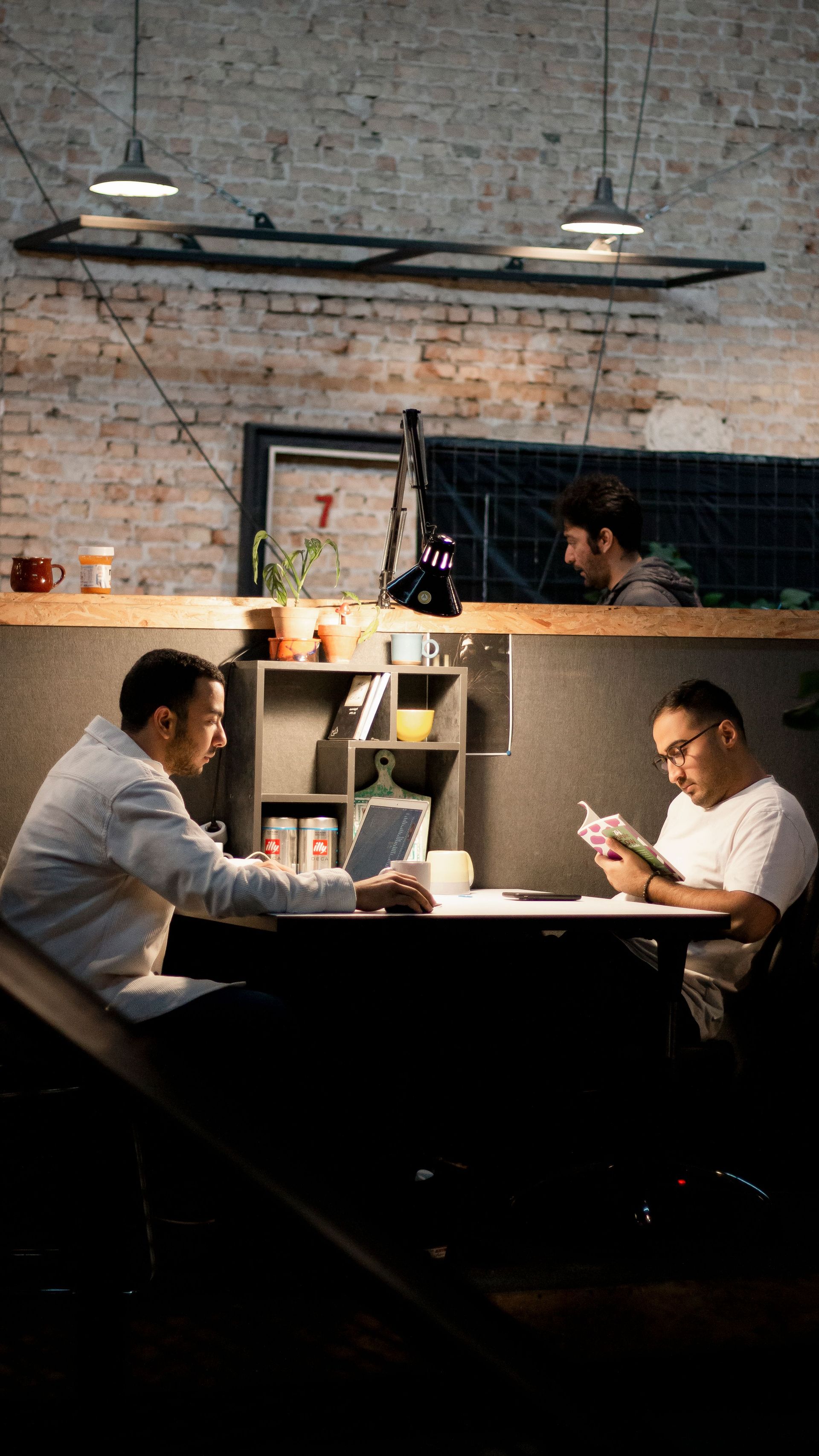 Two men relaxing and reading in a modern Tehran café. Cozy indoor ambiance.