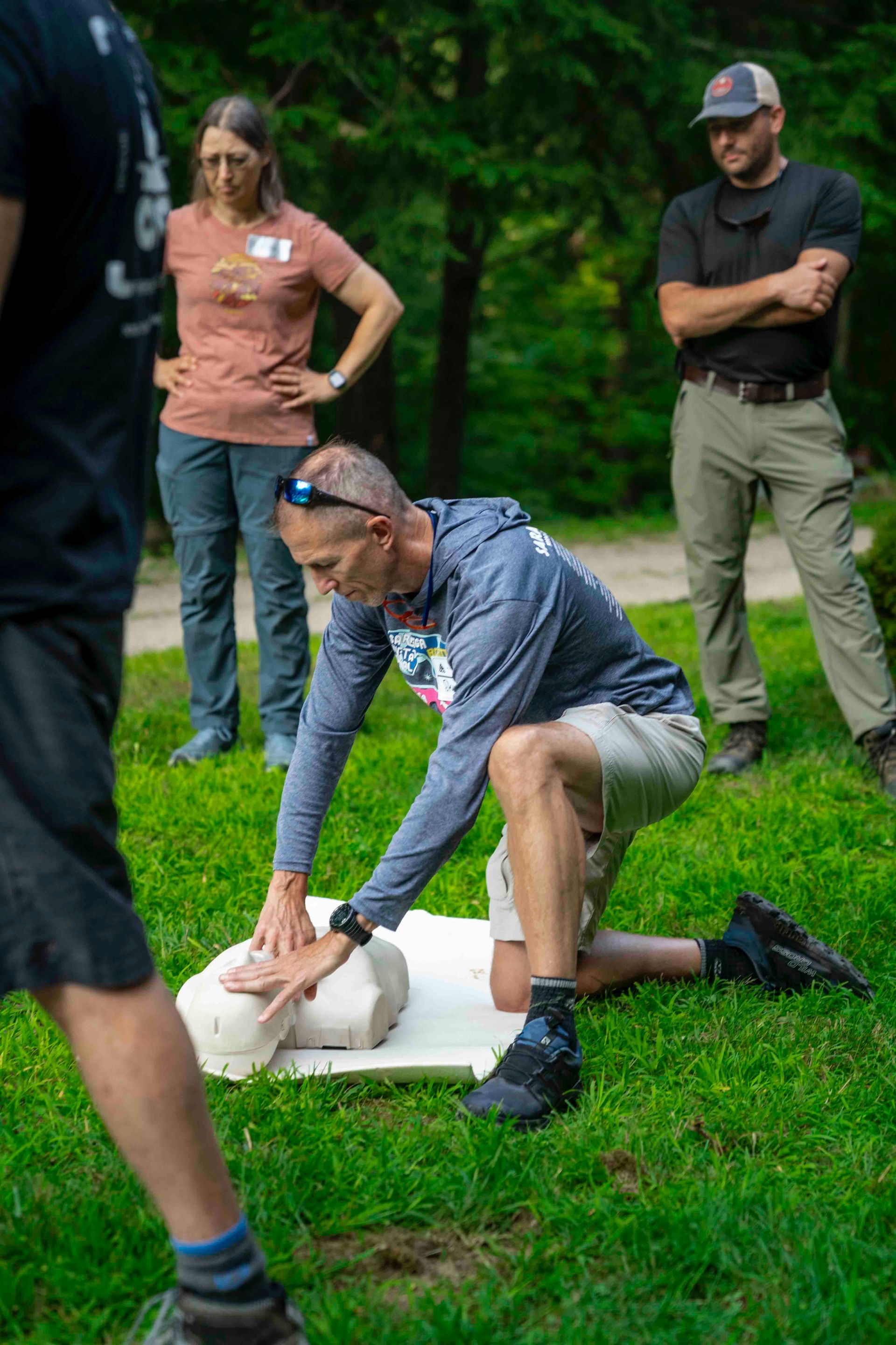 Man practices cpr on a dummy with others watching